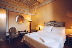 a bedroom with a bed and a chair and a mirror at Palazzo Rocchi B&B in Lucca