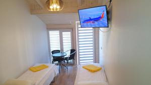 a room with a tv on a wall with a table at Apartamentai Relax Park in Šventoji