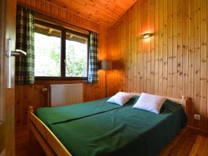 a bedroom with a green bed in a wooden wall at Pretty cottage Ardennes near the Valley of Lesse in Vencimont