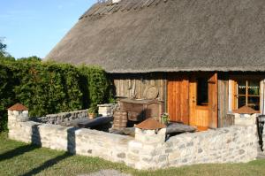 a small house with a thatched roof and a stone wall at Aadu Holiday Farm in Suur-Rootsi