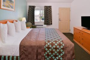 a hotel room with a large bed and a television at Americas Best Value Inn Los Banos in Los Banos