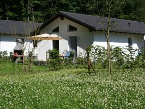 a white house with an umbrella and a field of flowers at Tidy holiday home with dishwasher, in a green area in Kopp
