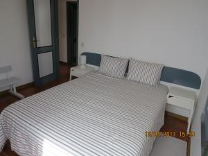 1 cama en un dormitorio con colcha a rayas en Casas do Zé Zambujeira do Mar, en Zambujeira do Mar