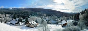 ein schneebedecktes Dorf mit Bergen im Hintergrund in der Unterkunft Hotel Kristian in Kubohütten