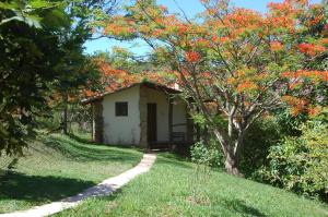 una pequeña casa de campo con un árbol con hojas rojas en Chalés de Minas Hotel Fazenda, en Caxambu