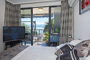 a bedroom with a television and a balcony with the ocean at Waterfront Escape in Nelson