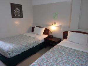 a hotel room with two beds and a night stand at Sakol Hotel in Nakhon Ratchasima