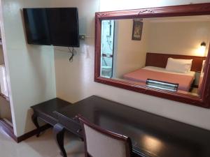 Cette chambre comprend un bureau, un miroir et un lit. dans l'établissement Sakol Hotel, à Nakhon Ratchasima