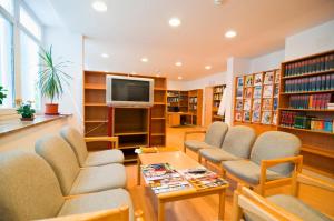 uma biblioteca com cadeiras e uma mesa e uma televisão em Kolpinghaus Bolzano em Bolzano