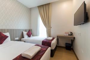 a hotel room with two beds and a flat screen tv at Signature International Hotel China Town in Kuala Lumpur