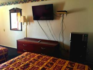Una habitación de hotel con una cama y un televisor en la pared. en Crown Inn Grand Prairie, en Grand Prairie