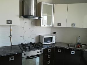a kitchen with a stove top oven next to a microwave at luxury family apartment in ain Zaghouan nord in El Aouina