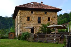 a stone building with umbrellas in front of it at Casona del Nansa in Herrerias