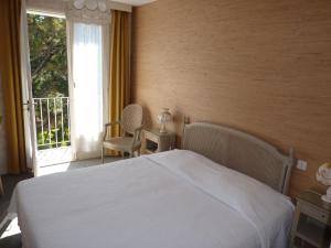 1 dormitorio con cama blanca y ventana en Hôtel La Concorde, en La Baule