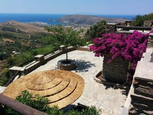 a patio with a table and purple flowers and the ocean at Anastasia Luxury Villas in Gavrio