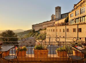 a balcony with tables and chairs in front of a building at Hotel Windsor Savoia in Assisi