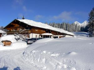 una casa cubierta de nieve con coches aparcados delante en Landhaus Wiederkehr, en Ramsau am Dachstein