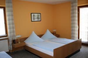 een slaapkamer met een bed met witte lakens en kussens bij Bergener Hof in Bergen