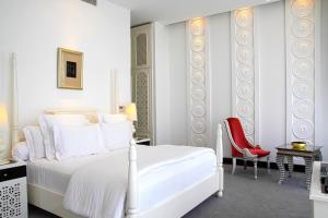 a white bedroom with a white bed and a red chair at Chloe Gallery in Ho Chi Minh City