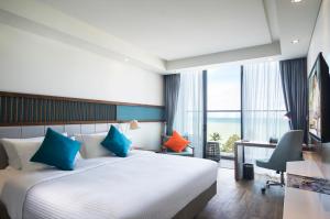 a hotel room with a bed with blue and orange pillows at Citadines Bayfront Nha Trang in Nha Trang