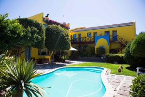 a swimming pool in front of a yellow building at Lagoon Loge in Walvis Bay