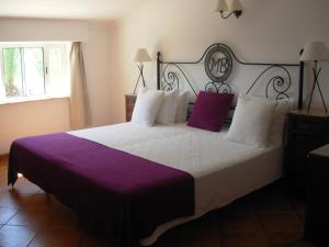 1 dormitorio con 1 cama grande con almohadas moradas y blancas en Monte da Bravura Green Resort, en Bensafrim