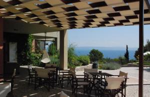 een patio met tafels en stoelen en uitzicht op de oceaan bij Astrolabe Hotel in Khrónia