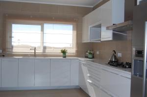 uma cozinha branca com armários brancos e uma janela em Villa Golf 6 em Óbidos