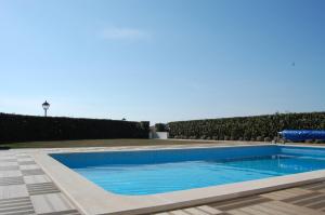 a swimming pool with blue water and a hedge at Villa Golf 6 in Óbidos