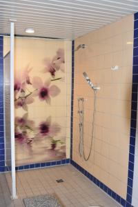 een badkamer met een douche met bloemen op de muur bij Landhotel Gillenfelder Hof in Gillenfeld