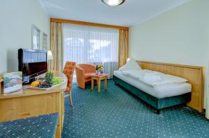 a hotel room with a bed and a couch and a table at PTI Hotel Eichwald in Bad Wörishofen