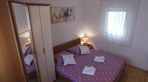 a small bedroom with a purple bed and a mirror at Apartment Branko Brodarica in Brodarica