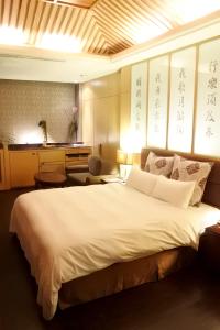 - une chambre avec un grand lit blanc et un bureau sur les murs dans l'établissement North Country Motel, à Yingge