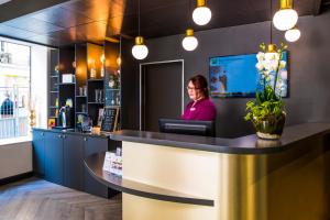 a woman sitting at a counter in a restaurant at ibis Styles Paris 15 Lecourbe in Paris