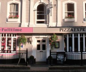 een roze en wit gebouw met een pizzeria bij The Merlin in Marlborough