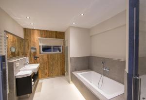 a bathroom with two sinks and a bath tub at HEITZMANN - Hotel & Rooftop in Zell am See