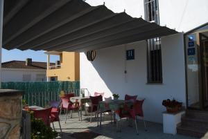 a patio with tables and chairs under a black umbrella at Hotel Paradís in Torredembarra