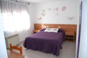 a bedroom with a purple bed and a window at Hotel Paradís in Torredembarra