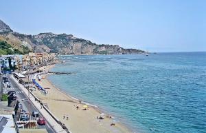 a beach with a group of people and the ocean at Tyttyhouse in Giardini Naxos