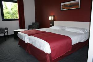 a bedroom with a large bed with a red wall at Hôtel AKENA La Ferté Bernard in Cherré