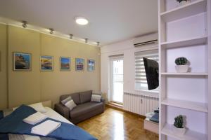 ein Schlafzimmer mit einem Bett, einem Sofa und einem TV in der Unterkunft Lux Life Apartment in Belgrad