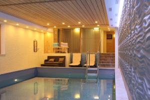 ein Swimmingpool in einem Zimmer mit einer Couch und Stühlen in der Unterkunft Hotel Bärenstüberl in Schönau am Königssee