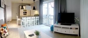 a living room with a flat screen tv and a kitchen at Apartamenty Nadmorska in Rowy