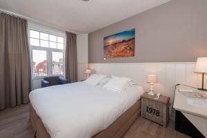 um quarto de hotel com uma cama grande e uma janela em Hotel Heritage em De Haan