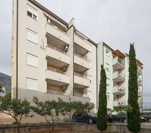 a large white building with trees in front of it at Apartment Meri Baska Voda in Baška Voda