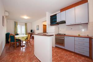 a kitchen with white cabinets and a table with chairs at Apartment Meri Baska Voda in Baška Voda