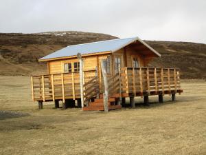 una pequeña casa de madera sobre pilotes en un campo en Smyrill Cottages, en Þórshöfn