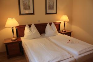 a bed with white pillows and two lamps on tables at Hotel Zachs in Sankt Margarethen im Burgenland