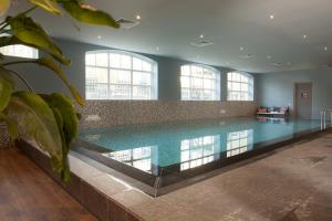 ein großer Pool in einem Gebäude mit Fenstern in der Unterkunft Grand Hotel Ter Duin in Burgh Haamstede