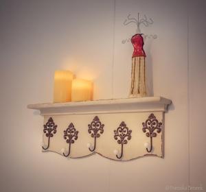 a shelf with candles and a red dress on it at Stone's throw Cottage Mevagissey in Mevagissey